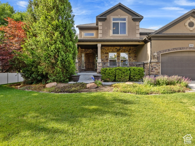 View of front of house featuring stucco siding, stone siding, a porch, a garage, and concrete driveway