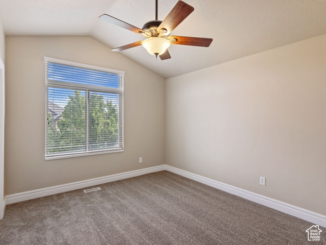 Unfurnished room with a ceiling fan, lofted ceiling, and carpet