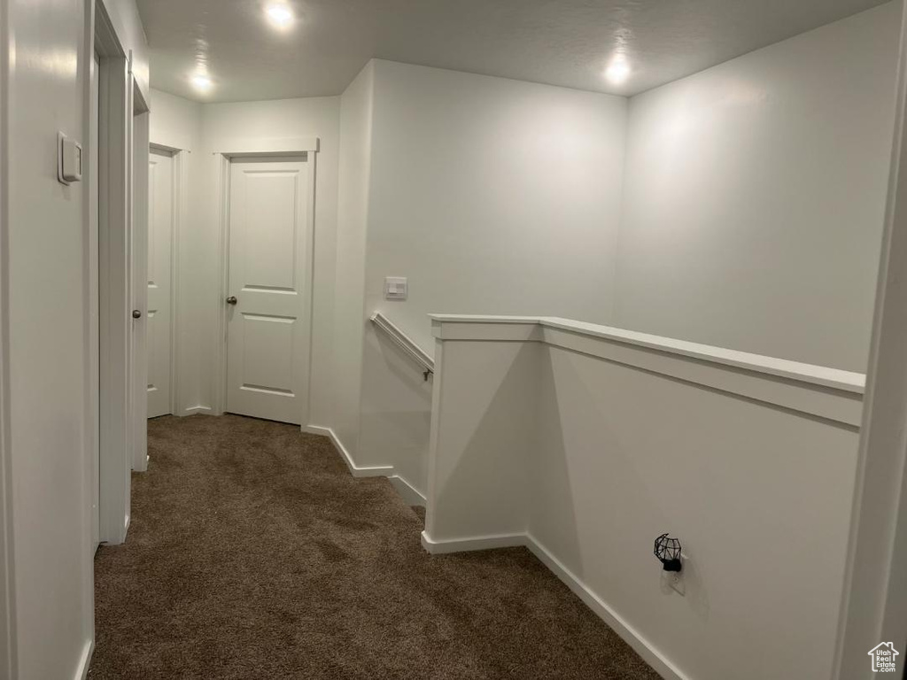 Hall featuring dark carpet and baseboards