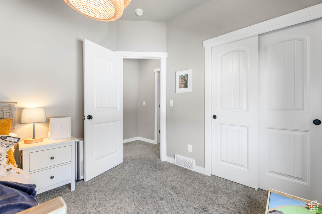 Bedroom with light colored carpet and a closet