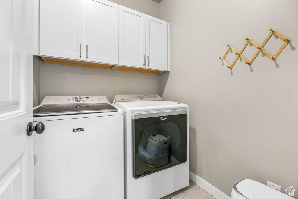 Laundry area with washer and dryer, cabinet space, and light tile patterned floors