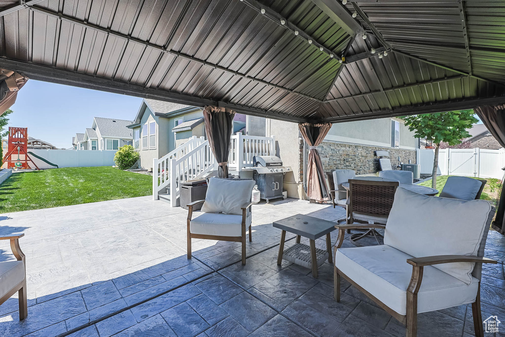Fenced backyard with a patio, a playground, and a gazebo