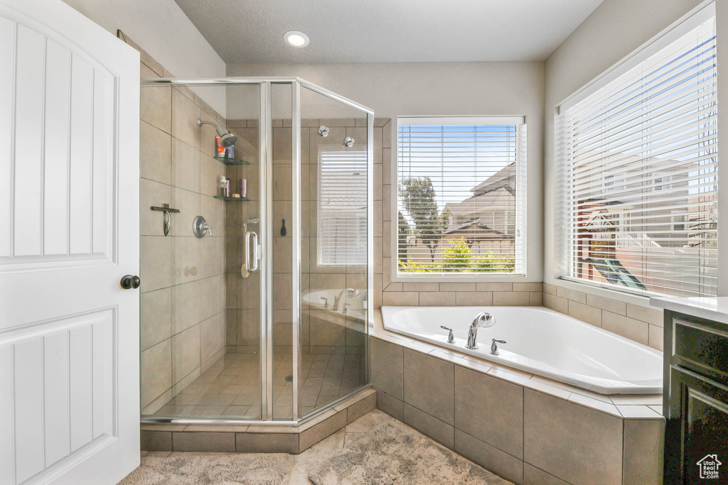 Bathroom with a bath, a stall shower, plenty of natural light, and tile patterned flooring