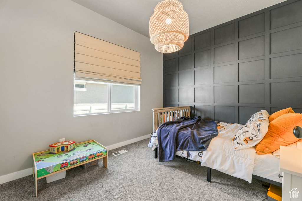 Carpeted bedroom featuring a decorative wall