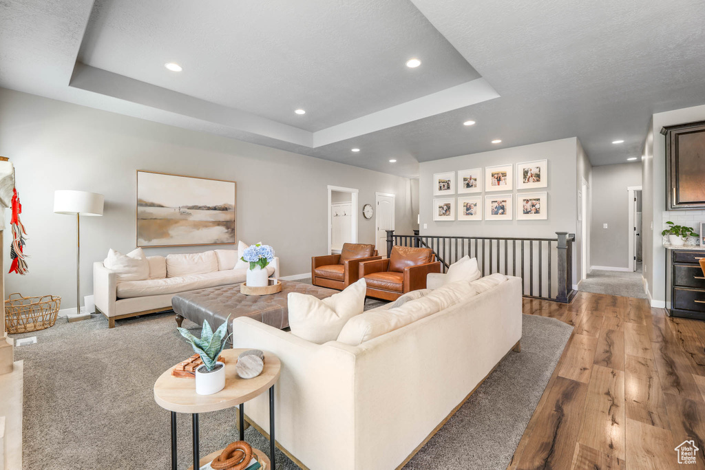 Living room featuring wood finished floors, recessed lighting, and a tray ceiling