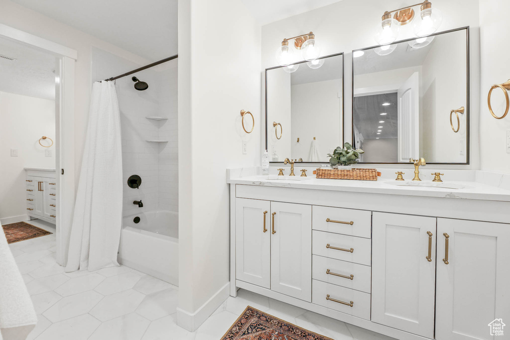 Full bathroom with double vanity, shower / bath combo with shower curtain, and tile patterned flooring