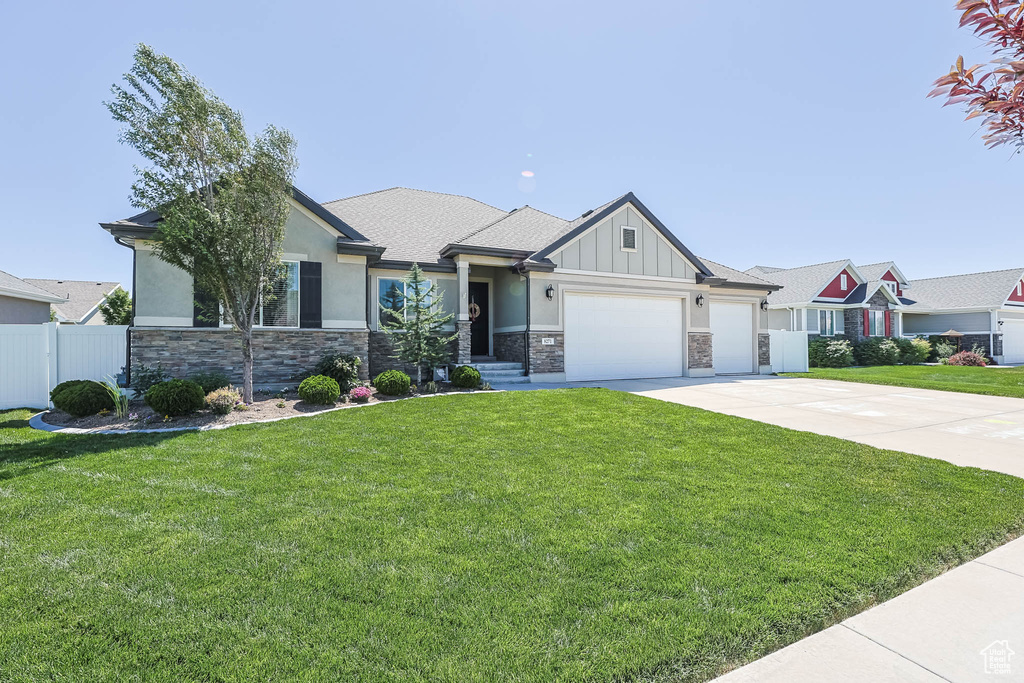 Craftsman-style house with stone siding, an attached garage, concrete driveway, board and batten siding, and stucco siding