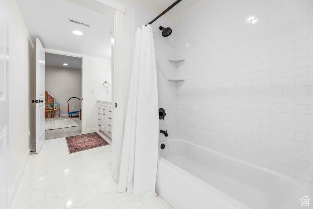 Ensuite bathroom featuring shower / bath combo with shower curtain, tile patterned floors, recessed lighting, and vanity