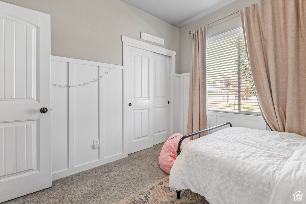 Bedroom featuring carpet flooring, multiple windows, and a wainscoted wall