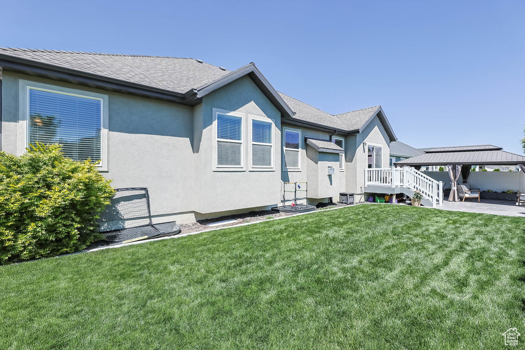 View of side of home with a gazebo, a yard, and stucco siding