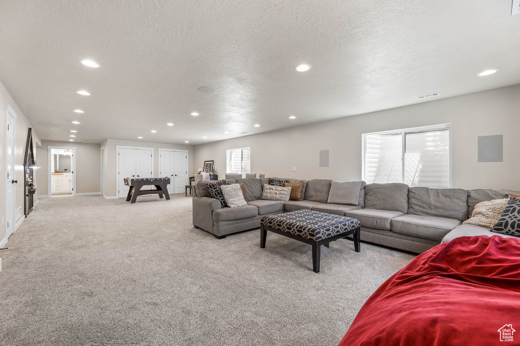 Living area with recessed lighting, light colored carpet, and a textured ceiling