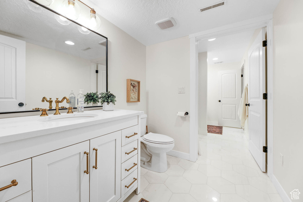 Bathroom featuring vanity, tile patterned flooring, and a textured ceiling