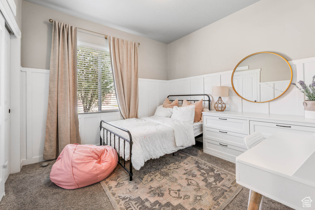 Carpeted bedroom featuring wainscoting and a decorative wall