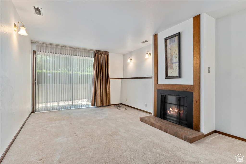 Unfurnished living room with carpet flooring and a glass covered fireplace