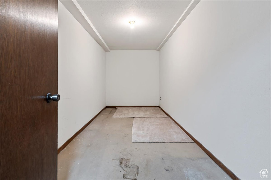 Unfurnished room with unfinished concrete flooring and baseboards