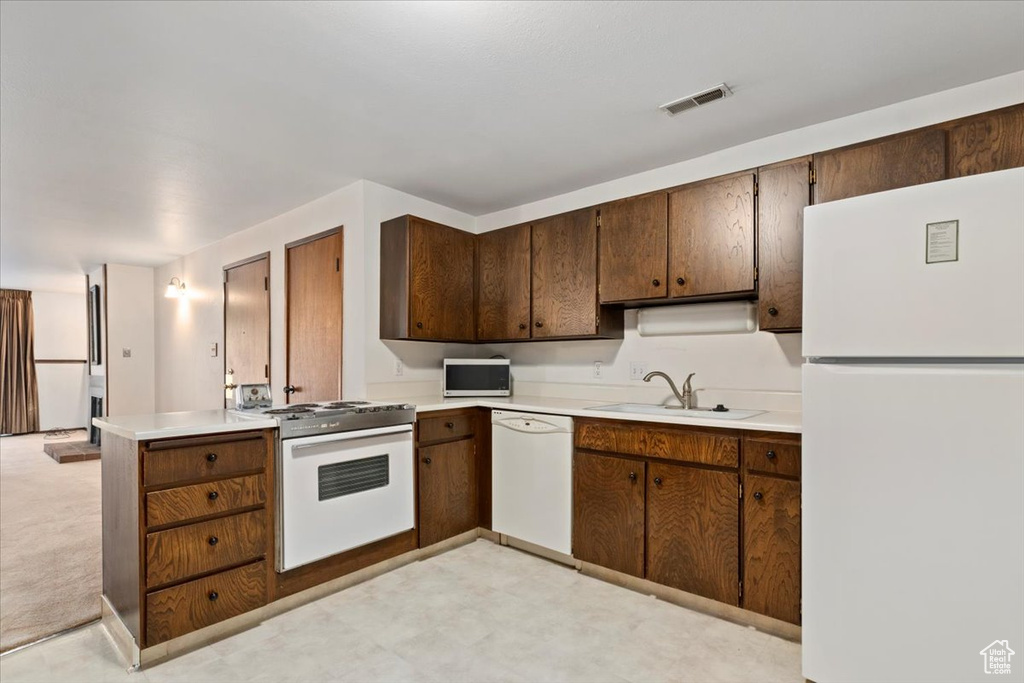 Kitchen featuring white appliances, light countertops, and a peninsula