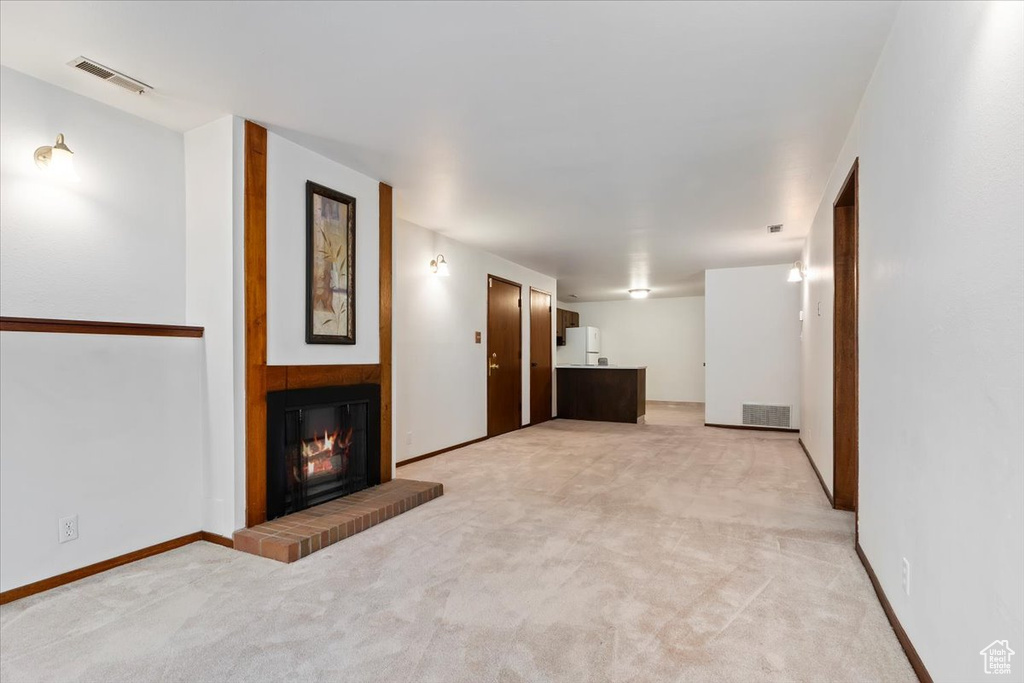 Unfurnished living room with light carpet and a glass covered fireplace