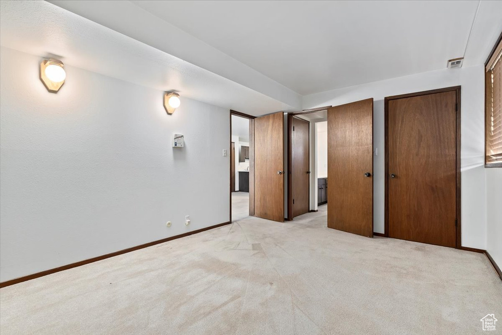 Unfurnished bedroom featuring light colored carpet and multiple closets