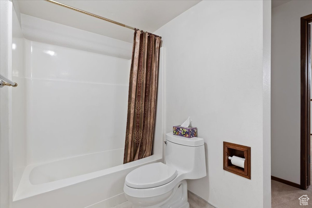 Full bath featuring toilet and shower / bath combination with curtain