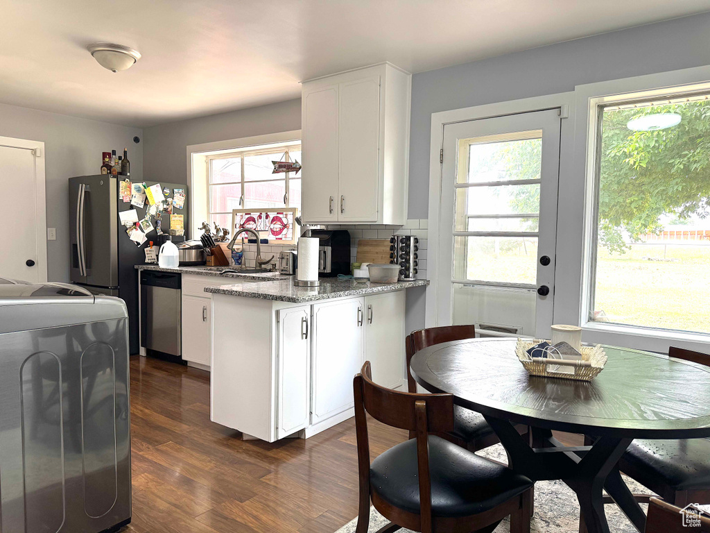Kitchen featuring dishwasher, white cabinets, range, dark wood-style flooring, and a peninsula