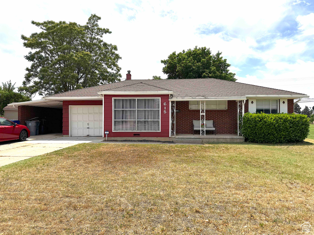 Single story home with covered porch, a front yard, concrete driveway, an attached garage, and a carport