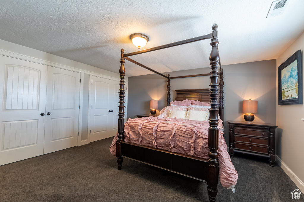 Bedroom with dark carpet and a textured ceiling