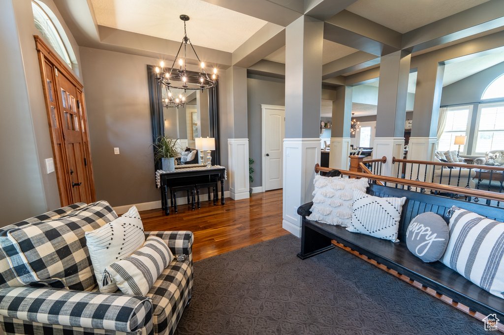 Living room featuring a chandelier, wood finished floors, and ornate columns