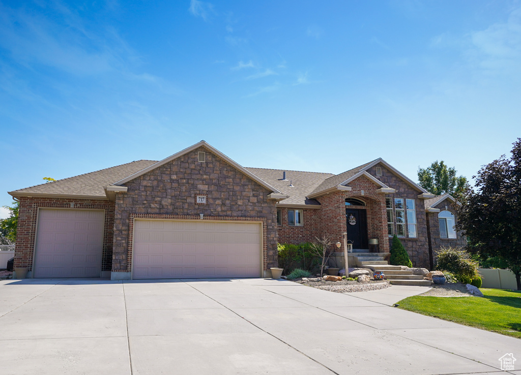 View of front of home featuring a garage, concrete driveway, a shingled roof, and brick siding
