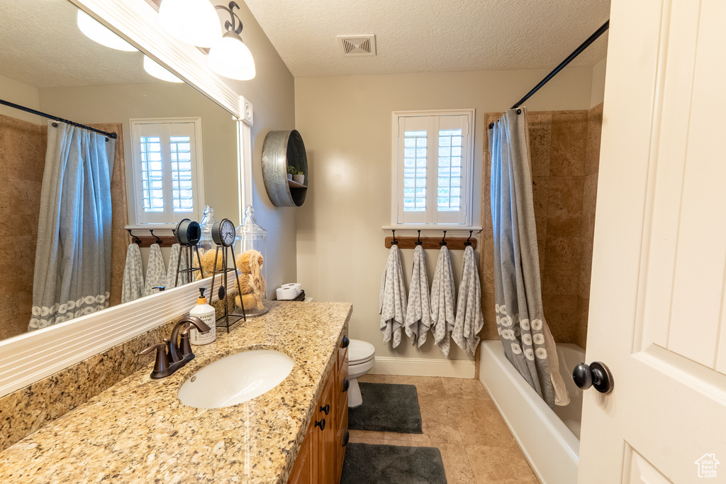 Bathroom with vanity, a textured ceiling, tile patterned floors, and shower / bath combo
