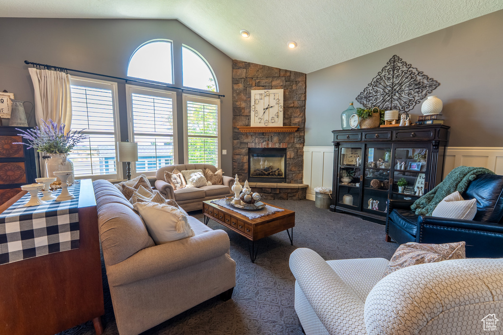 Living area with a wainscoted wall, lofted ceiling, carpet floors, a fireplace, and a decorative wall