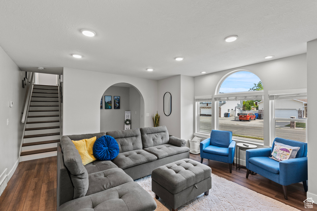 Living room with arched walkways, wood finished floors, stairway, and recessed lighting