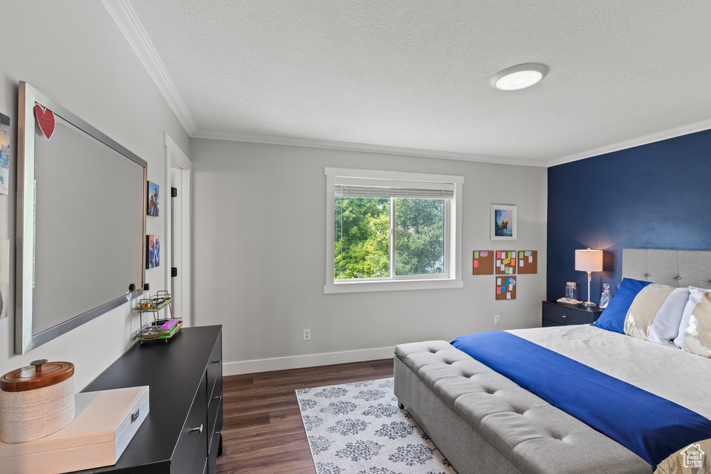 Bedroom featuring ornamental molding, dark wood-type flooring, and a textured ceiling