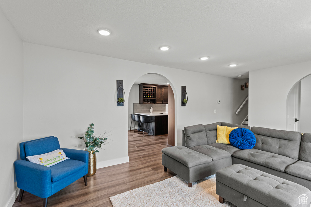 Living room featuring arched walkways, stairs, wood finished floors, and recessed lighting