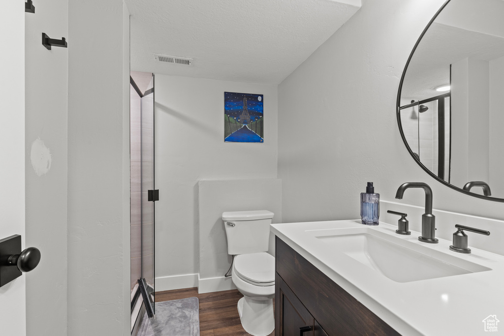 Bathroom with wood finished floors, a shower stall, and vanity