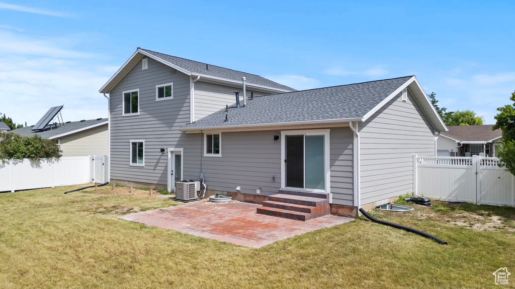 Rear view of house featuring entry steps, a patio, a fenced backyard, a shingled roof, and a gate
