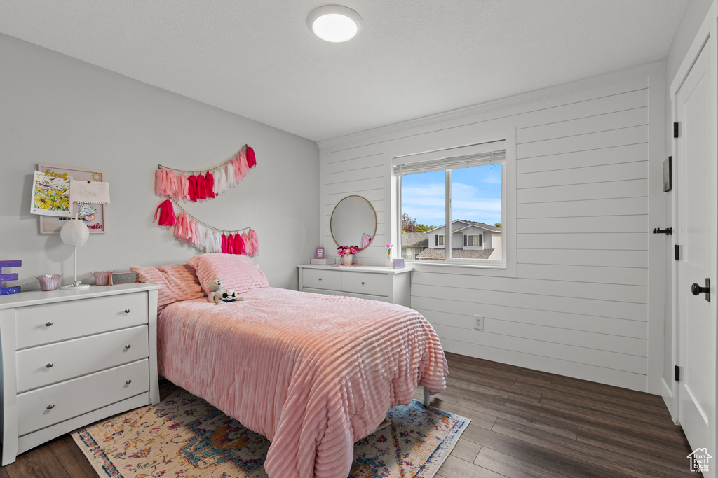 Bedroom with wood finished floors and wood walls