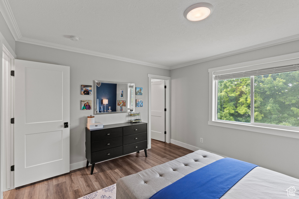 Bedroom with wood finished floors and crown molding