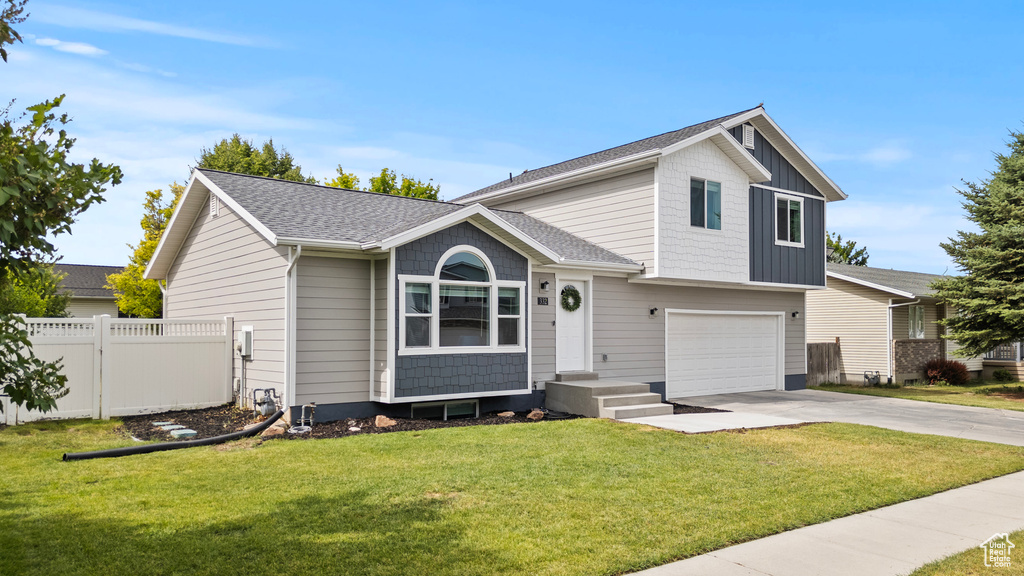 Tri-level home with a garage, driveway, and roof with shingles