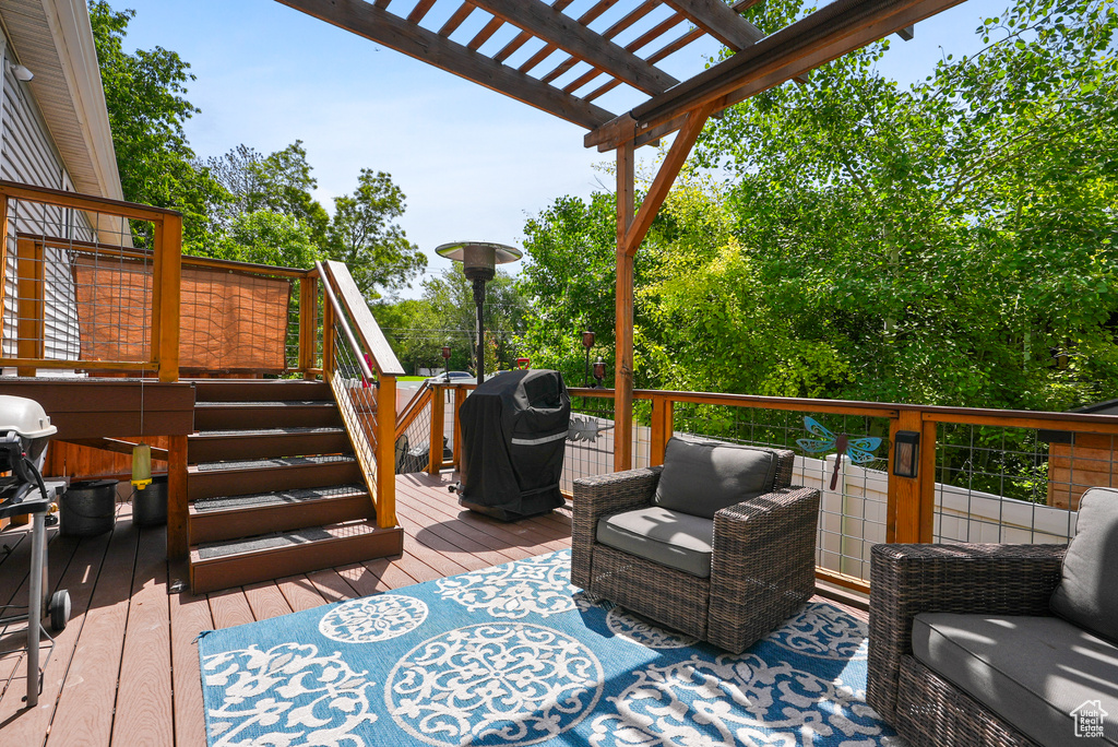 Wooden terrace with grilling area, a pergola, and outdoor lounge area
