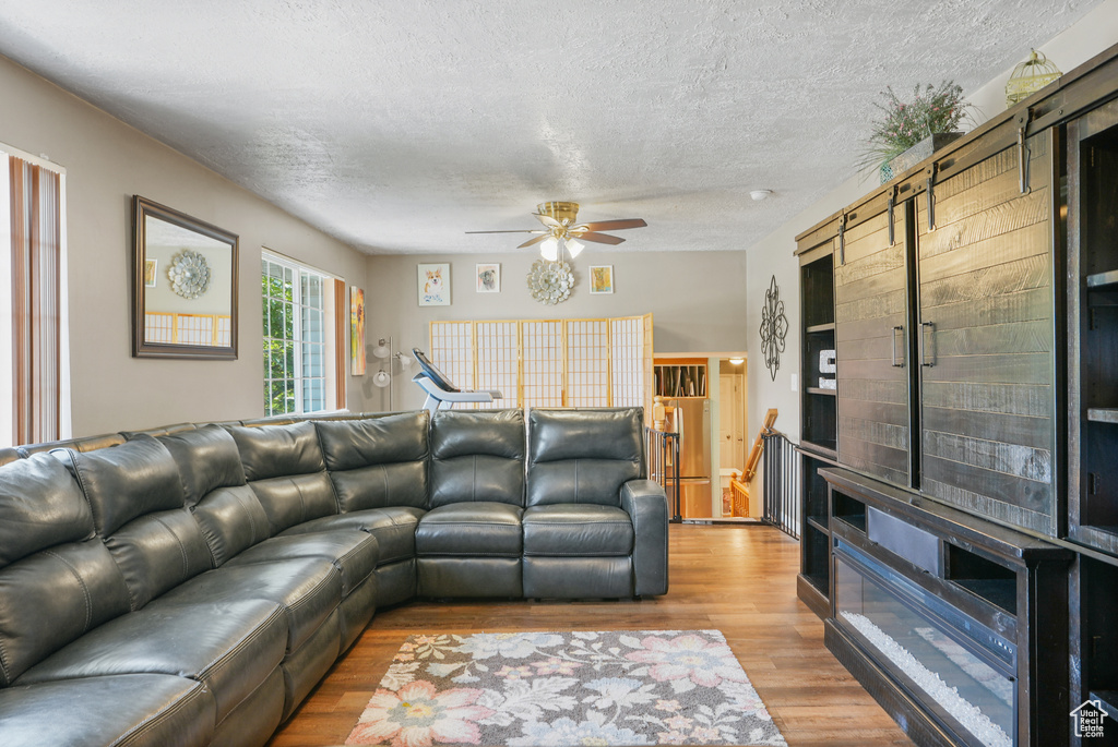 Living room with a textured ceiling, ceiling fan, and wood finished floors