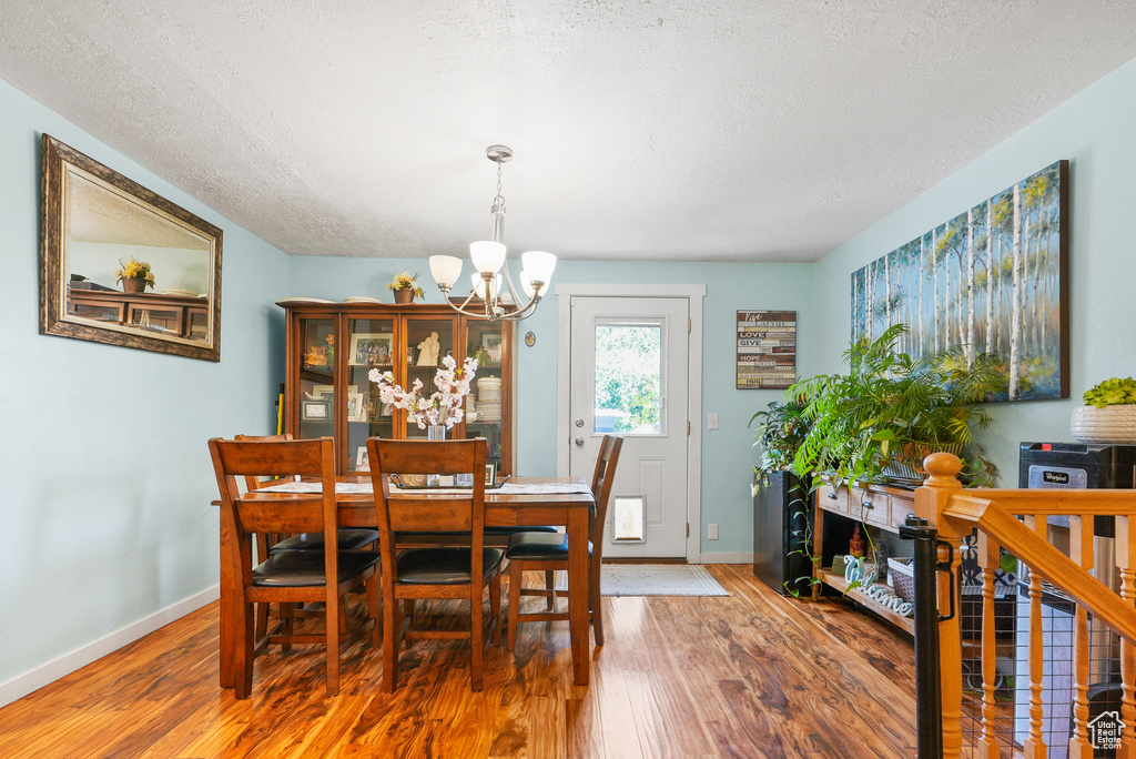 Dining room with a chandelier, wood finished floors, and a textured ceiling