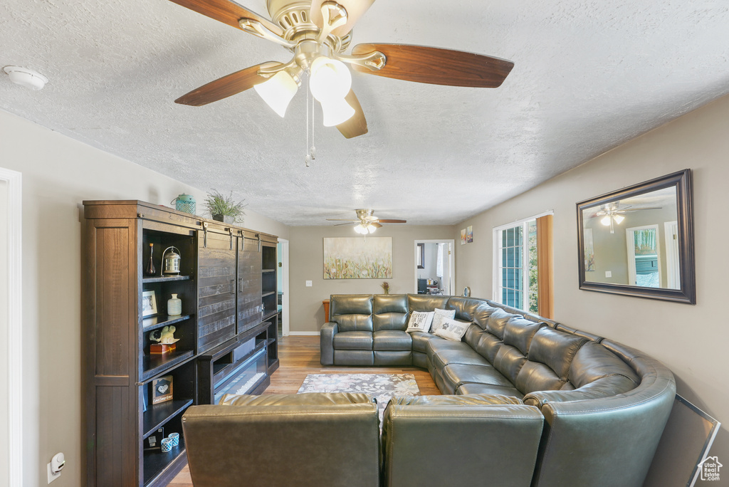 Living room featuring wood finished floors, a textured ceiling, and a ceiling fan