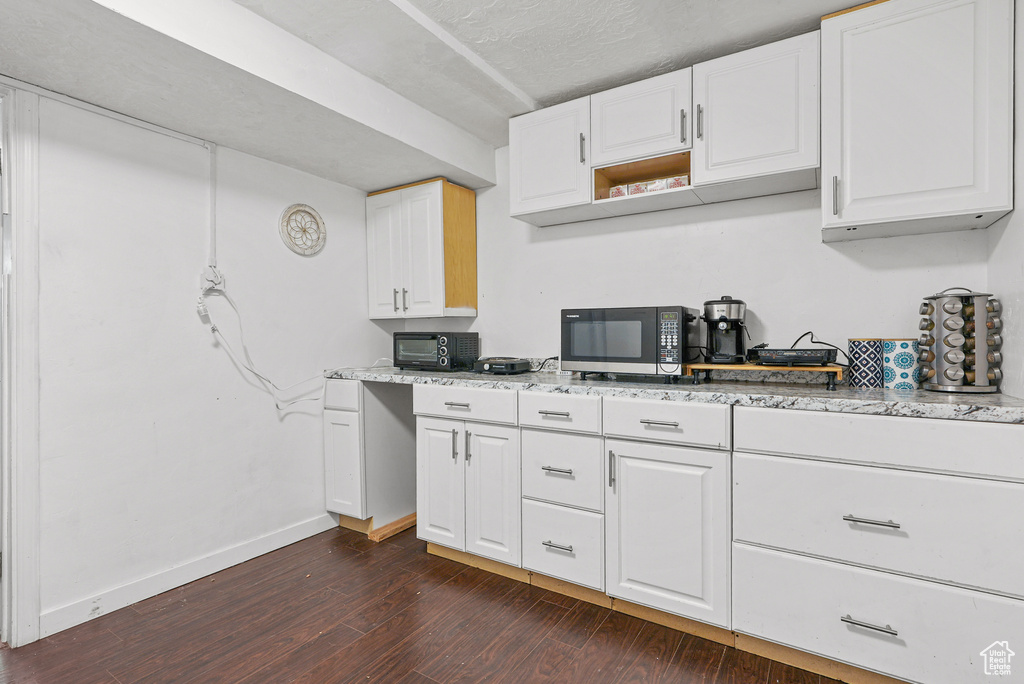 Kitchen featuring dark wood-style floors, white cabinetry, light stone countertops, and open shelves