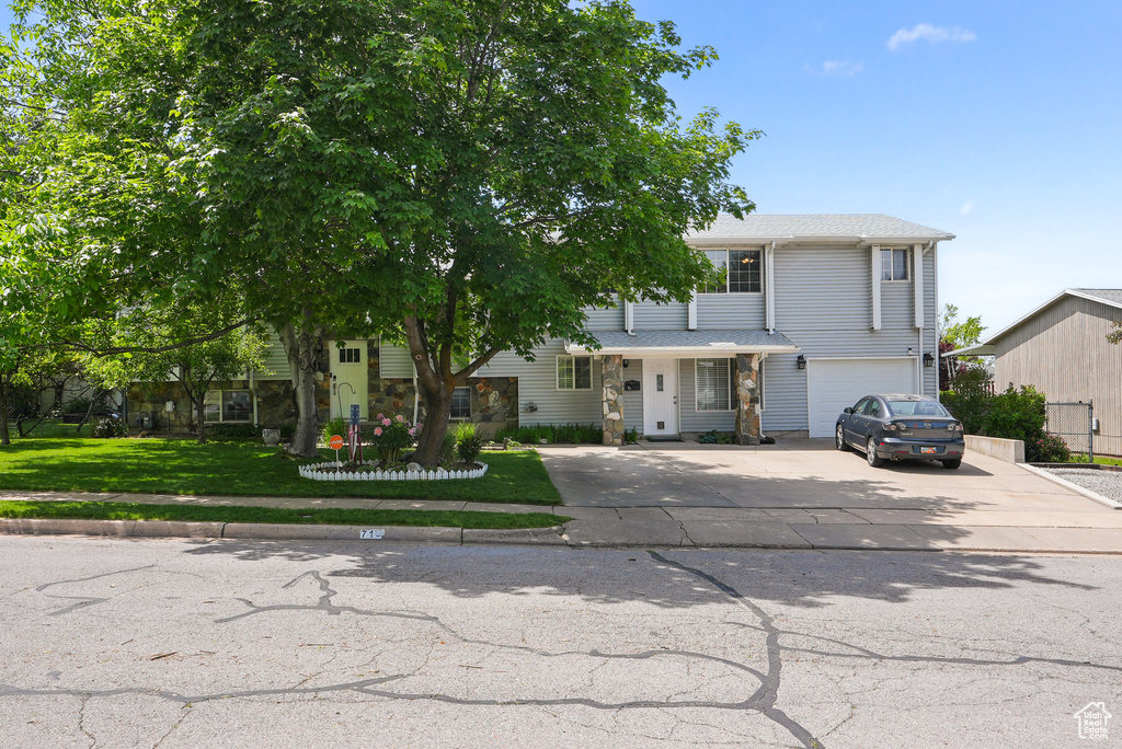 View of front facade with driveway, an attached garage, and a front yard