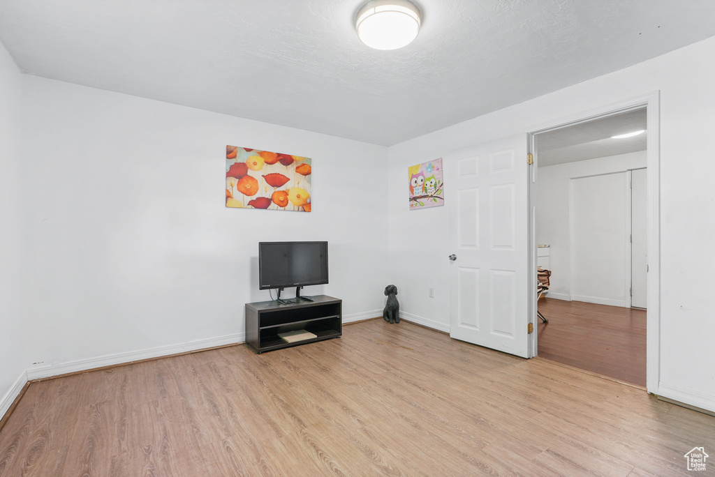 Unfurnished living room with light wood-style flooring and baseboards