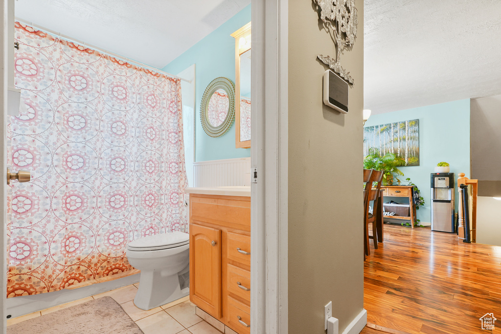 Bathroom with vanity, shower / tub combo, wood finished floors, and healthy amount of natural light