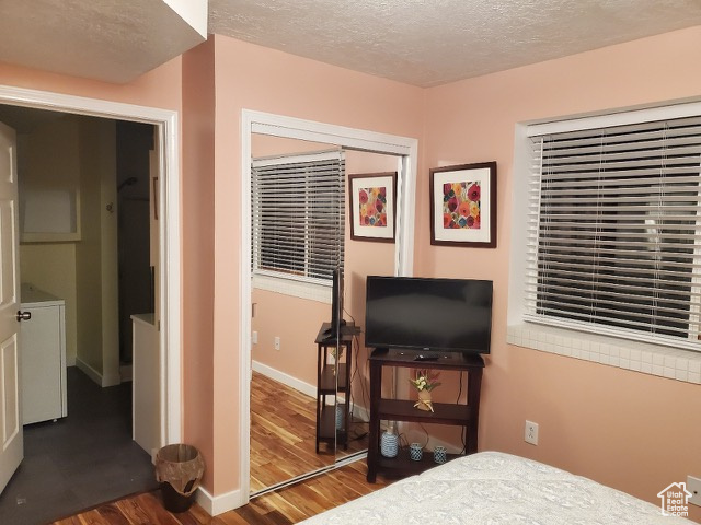 Bedroom featuring wood finished floors, a textured ceiling, and washer / clothes dryer