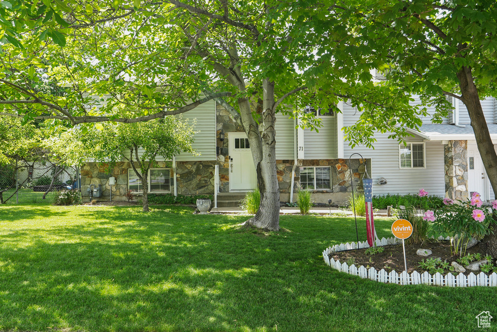 View of front facade featuring stone siding and a front yard