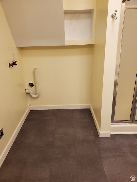 Washroom with electric dryer hookup, hookup for a washing machine, and dark tile patterned flooring