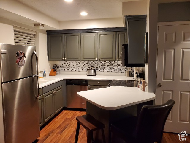 Kitchen with stainless steel appliances, a peninsula, light wood-style flooring, light countertops, and recessed lighting